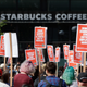 A Starbucks Coffee shop is seen in the background as people gather at Westlake Park during the "Fight Starbucks' Union Busting" rally.